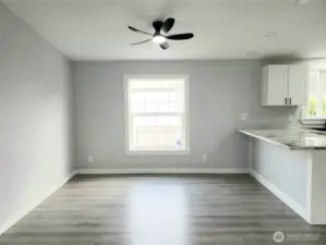 A View of the Dining Room and Kitchen showing the Breakfast Eating Bar from the Huge Living Room with Cathedral Ceilings, New Paint Trim and Vinyl Plank Flooring.