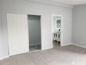 A View of the Primary Master Bedroom Showing Cathedral Ceilings, All New Paint, Trim and Carpeting Looking into the Walk In Closet and Primary Master Bath Room.