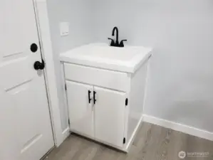 Nice Utility Room with a New Deep Utility Sink Vanity, Faucet, Paint, Trim, And Vinyl Plank Flooring.