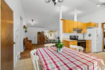 Kitchen and dining area with wood cabinetry, tile flooring, and open connection to the main living space.