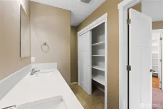 Primary bathroom with large linen closet and toilet hidden behind wall for added privacy
