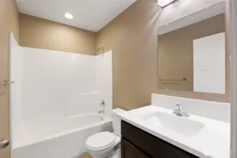 Main bathroom features tub & shower, ceramic tile flooring, white quartz countertops & backsplash