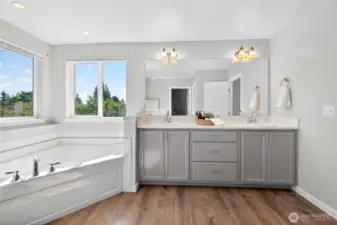 Ensuite featuring double vanity and large soaker tub with natural light