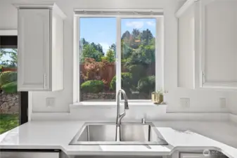 Enjoy serene backyard views with mature landscaping from the kitchen sink window
