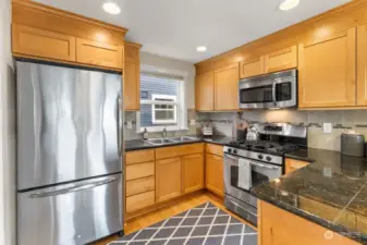 The kitchen is a well designed space with an eat-in peninsula, gas range, stainless steel appliances, granite countertops, and a spacious walk-in pantry.