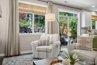 Huge picture windows and a sliding glass door look out to a private backyard setting.