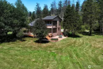 View of main house from yard. Surrounded by mature trees that allow plenty of sunshine on deck and patio.