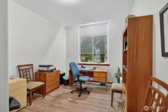 Den features tall ceilings that enhance the sense of spaciousness, complemented by a large closet. The room showcases luxury vinyl planking, seamlessly extending from the hallway to create a cohesive flow throughout the space.