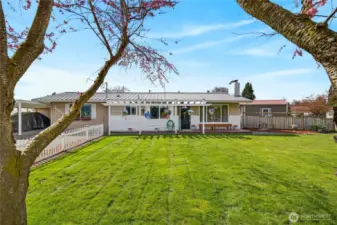 Charming single-level home with a spacious yard, covered patio with pergola, and inviting outdoor space perfect for relaxing or entertaining.