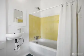 The full bath is accessible from the utility room or the bedroom and has a newer (vintage) sink and the original cast iron bath tub with the tile surround.