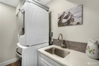 Laundry with full-size stack, utility sink & hanging rod.