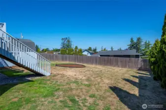 Upper deck stairs down to fenced back yard with garden area.