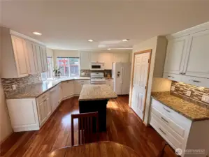Kitchen with Huntwood cabinets with soft close doors, many pullout drawers, which are made with plywood boxes and solid maple doors factory painted finished in a colonial white.  There is slab granite counters.  The island is an Espresso color with corbels and decorative back for a finished look.  Acacia engineered floors throughout most of the downstairs.