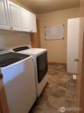 Laundry room with access to the garage and extra cabinet storage above the washer and dryer and additional storage cabinets on the right.  The laundry room is roughed in for a future sink near the door.
