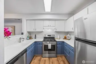 Renovated kitchen with deep slate-blue cabinetry, white quartz counters, and a bright coastal backsplash.