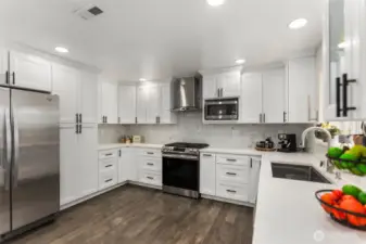 The chef's kitchen is a dream, featuring a generous island, gas cooktop with hood!