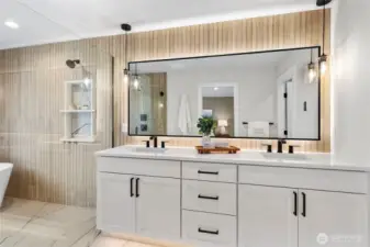 This primary bathroom is a stunning blend of elegance and modern design, featuring a double-sink vanity with sleek black accents and warm wood textures. From the glass-enclosed shower to the freestanding tub and ambient lighting, every detail contributes to a spa-like retreat that’s both functional and luxurious.