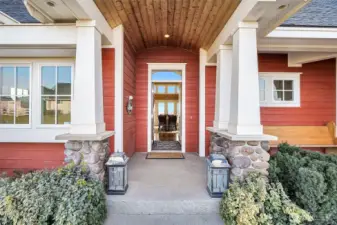 What a beautiful front entry porch with farmhouse-style colors in a custom, Craftsman-built home filled with natural light from the vast arrays of windows surrounding the walls of the great room!