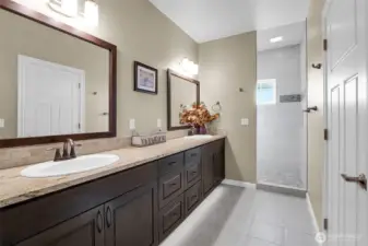 As you enter the primary bathroom from the bedroom door on the right, you'll find yourself in the luxury of privacy in the custom tiled shower facing the back of the home. The luxurious, rich dark cabinetry holds a multitude of necessities. Behind you is the water closet.