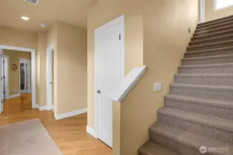 The staircase makes a statement—graceful, open, and timeless. The rug on the wooden floor hosts the front/side door entry, making it quick to add your coat to this closet, and head up the stairs to the additional living space or down the hall to your left to the pantry and kitchen area.