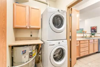 A handsome stack washer/dryer setup with a folding table and storage cabinet.