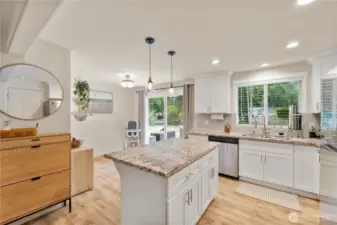 The kitchen features gorgeous white, soft close cabinetry with decorative pulls, slab granite countertops & updated stainless appliances