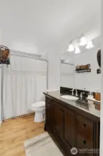 The refreshed bath includes a beautiful vanity with granite countertop, tile surrounded shower, laminate floor & newer toilet