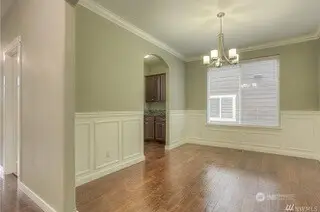 Warm-toned, hand-scraped engineered wood floors set the tone, while the arched doorway to the dining room adds that extra touch of elegance. The neutral walls and crisp white trim create a calm and inviting space, and the open layout leads effortlessly from the dining room to the casual eating area in the kitchen, with the family room just a few steps away.