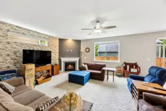 This family room just keeps getting better. With all the same cozy elements, accent wall, gas fireplace, and classic white mantle, this shot reveals the hidden genius of a long upper landscape window on that textured accent wall. It lets in even more light without sacrificing precious furniture placement. So go ahead, set up your couch under that window and bask in the glow, literally and figuratively. This room is not just functional, it's got that "I can’t wait to hang out here" vibe.