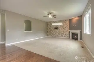 This family room is the heart of the home, with a striking full accent wall that adds a pop of texture and style. The darker accent wall behind the gas fireplace with its elegant tile surround and white mantle gives the room a touch of sophistication. The plush carpeting makes it cozy and inviting, while the large picture window overlooking the backyard brings the outdoors in. It’s a space designed for both comfort and conversation.