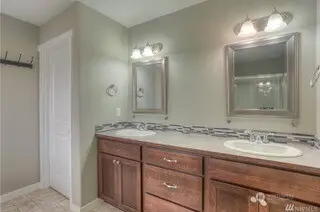 Let’s talk about this primary suite bathroom, it’s spacious, practical, and full of style. The long vanity with two sinks ensures there’s enough room for both of you to get ready without any chaos. The coffee-tone shaker cabinetry is warm and inviting, and the two separate framed mirrors make this space feel even bigger. Vinyl flooring means easy maintenance, and the "water closet" is tucked away for privacy. And let’s not forget that deep soaking tub, it’s calling your name after a long day. Go ahead, take a moment for yourself.