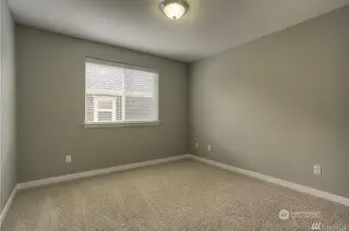 Simple and serene, this 4th bedroom is designed with the same neutral tones and white trim found throughout the home. The carpeting adds a soft, cozy touch, and the wide slat blinds let you control the light and privacy. Whether you need an extra bedroom, a home office, or a place to unwind, this room is the perfect blank canvas for whatever your needs may be.