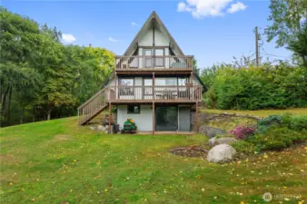 Light-filled open-beam design with a loft, flexible lower level, and deck overlooking fruit trees + greenhouse.