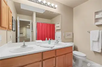 Full upstairs bathroom offers dual vanity and natural light from a skylight.