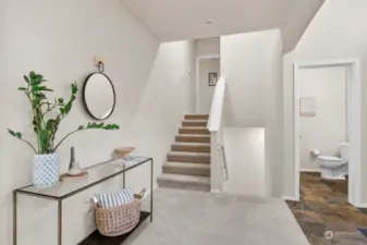 Half bath off of the entry, and stairs leading up to primary bedroom and down to garage-entry level.