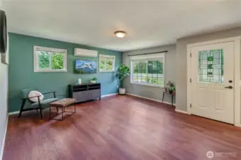 Light, bright, and welcoming! This spacious living room features large windows, rich flooring, and a mini-split system for year-round comfort. The perfect place to unwind and feel at home.