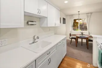 Enter into a clean galley kitchen that is nicely updated with bamboo floors and white cabinets and appliances.