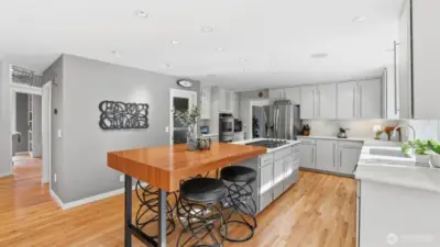 The newly refreshed kitchen shines with quartz counters, an extended island with custom eating bar, abundant cabinetry and walk-in pantry.