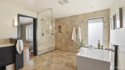 Spa-inspired bath features dual vanities, heated travertine floors, a generous soaking tub, a separate travertine shower, and a spacious walk-in closet.