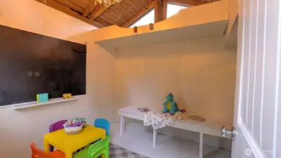Playhouse is ready for fun.  Note the loft above. There is a ladder to access! Also, a bookcase behind the door.