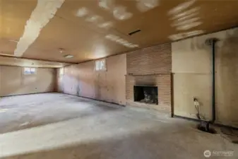 Expansive basement with matching brick fireplace.