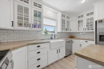 This bright kitchen offers a farmhouse sink, loads of cabinets and ample counter space.