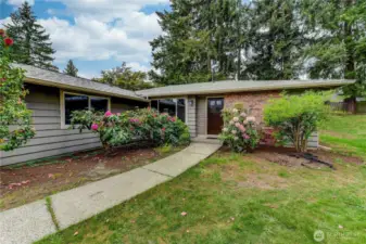 Nestled on a quiet street, this charming rambler boasts a beautifully landscaped front yard framed by mature trees and vibrant blooms.