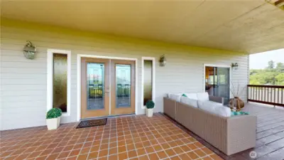 Tiled entry way which extends into interior entry way with double glass doors and outdoor living space.