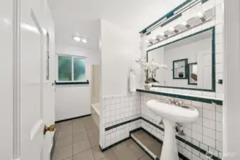 Main bath off hallway features retro style tile with mirrored alcoves and tile ledge. Tub and shower beyond the wall.