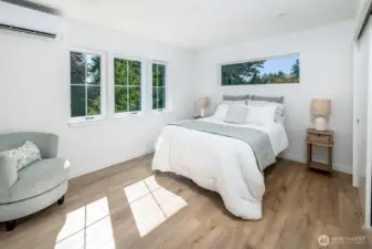 Primary bedroom with lush tree views from every window!  Natural wood grain design floors through this canopy suite.  Notice that the builder added two light switches on either side of the bed for easy control of detailed lighting.