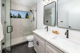 Primary bedroom ensuite bathroom with dual sink vanities, and huge walk in shower.  Heated tile floors keep you comfortable and warm, and the tree view is a welcoming site each day.