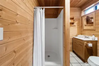 3/4 bath has tiled floors and storage space under the sink.