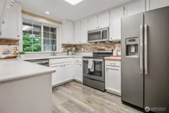 Galley kitchen includes LVP    flooring, stainless-steel appliances