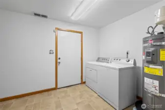Laundry area located in the basement with a door to the back yard